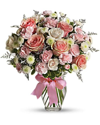 <p>This charming mix includes pink roses, pink spray roses, miniature carnations, white button spray chrysanthemums, and lavender limonium. Lush green pittosporum adds contrast and texture, while a clear glass vase wrapped with a pink satin ribbon completes the polished, gift-ready presentation.</p>
