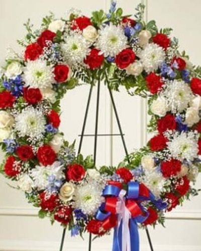 <p>The Serene Sympathies Standing Wreath in red, white, and blue is a dignified expression of remembrance, handcrafted to offer comfort and gratitude during a time of loss. This striking wreath features a patriotic blend of fresh red and white roses, vivid blue delphinium, and lush greenery.</p>