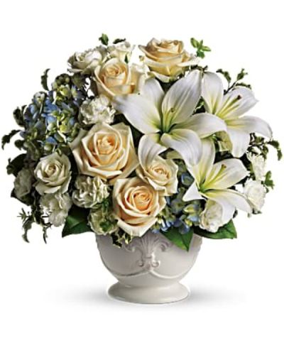 <p>This soothing design features blue hydrangea, cream roses, white miniature carnations, and fragrant white asiatic lilies. The flowers are arranged in a rustic French country pot, offering timeless and understated elegance that complements the sentiment behind the gift.</p>