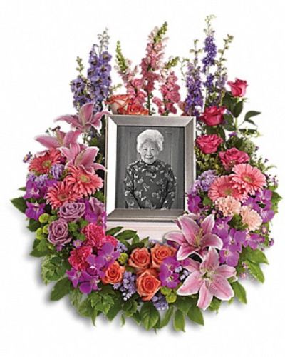 <p>Honor a cherished life with a wreath that beautifully expresses devotion and lasting memories. The arrangement features a rich mix of blooms including purple orchids, asters, orange, dark pink, and lavender roses, as well as pink and peach carnations.</p>
