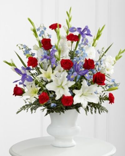 <p>This bouquet features white lilies, deep red roses, and striking blue delphinium and irises, each bloom chosen to represent purity, love, and remembrance. The lilies may arrive in bud form, symbolizing life continuing to unfold and offering renewal and reflection as they bloom in the days ahead.</p>