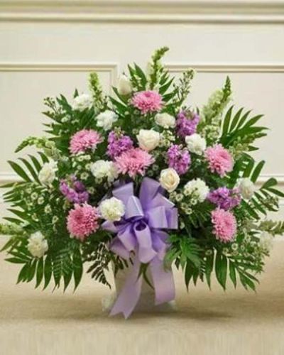 <p>The Touching Tribute Floor Basket in lavender and white is a tender way to honor a loved one and share your sympathy with those who are grieving. This elegant arrangement features a soft mix of white roses, snapdragons, and carnations, paired with soothing lavender mums, lavender stock, and additional seasonal accents.</p>