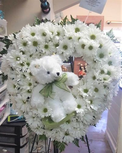 <p>This sweet wreath features a soft keepsake stuffed bear nestled among a lush ring of fresh blooms. Designed with care and creativity, the arrangement combines cheerful florals in soft tones with playful charm, creating a gift that brings comfort, warmth, and a smile.</p>