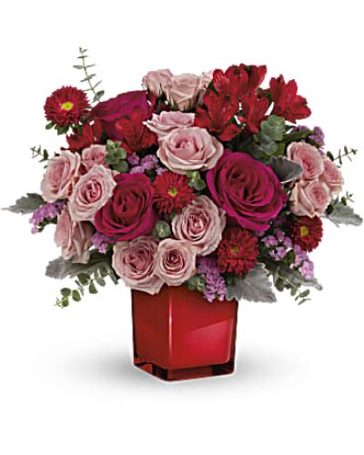 <p>This eye-catching arrangement features hot pink roses, delicate pink spray roses, red alstroemeria, and red Matsumoto asters. The bouquet is presented in a sleek crimson glass cube vase, which glows with contemporary elegance and can be reused as a stylish candleholder or accent piece.</p>
