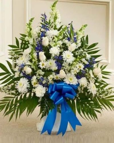 <p>The Touching Tribute Floor Basket in blue and white is an elegant expression of sympathy, crafted to honor a cherished life with grace and dignity. This refined arrangement features a soothing blend of white roses, snapdragons, and carnations, paired with striking blue delphinium and complementary seasonal blooms.</p>